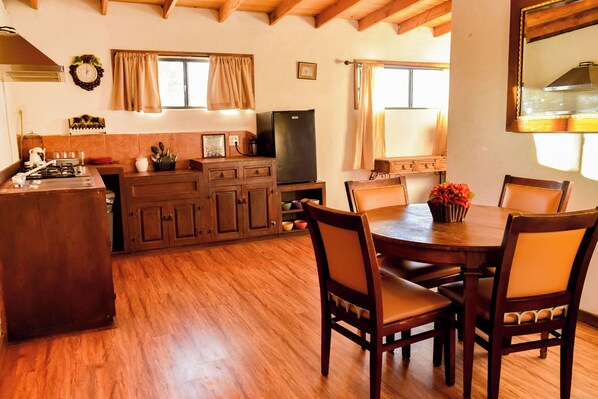 A kitchen with wooden cabinets, a dining table with chairs, and a television.