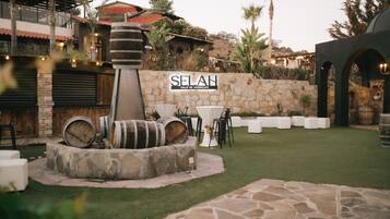 Ein Terrassenbereich im Freien mit Steinmauern, einem Schild mit der Aufschrift "SELAN VALLE DE GUADALUPE" und rustikalen Fässern.