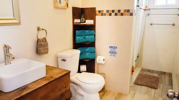 A bathroom with a white sink, a toilet, and a shower area.