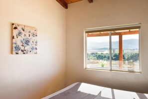A room with a large window, a painting on the wall, and a wooden ceiling. - Finca Selah (Valle de Guadalupe)