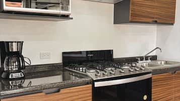 A modern kitchen with wooden cabinets, a microwave, a gas stove, and a coffee maker.