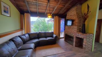 Una sala de estar con un sofá de cuero curvo, una chimenea de ladrillo y un televisor montado en la pared.