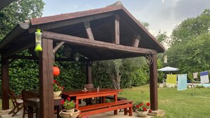 A wooden pergola with a table and chairs, surrounded by potted plants and a string of lights. - Beautilful rustic country house totally imersed in the county of Marche (Marche)