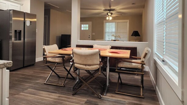 A modern kitchen with a dining area, including a table with chairs, a refrigerator, and a ceiling fan. - Brand new ranch offers a beautiful layout, outdoor areas and 3 spacious bedrooms. (Concord)