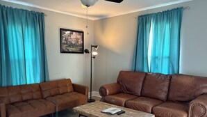 A living room with two brown leather sofas, a wooden coffee table, a floor lamp, and a framed picture on the wall.