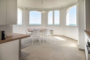 Uma cozinha moderna com área de jantar, janelas amplas e vista para o mar.