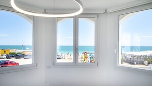 A room with large windows, a circular light fixture, and a view of the beach. - M447 - Marcelli, brand new sea front three-room apartment in a residence with swimming pool (Marcelli)