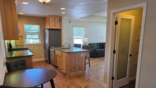 A modern kitchen with wooden cabinets, a built-in island, and a dining area with a table and chairs.