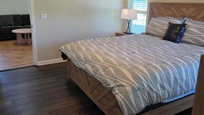 A bedroom with a bed, a ceiling fan, a nightstand, a lamp, and a window with blinds.