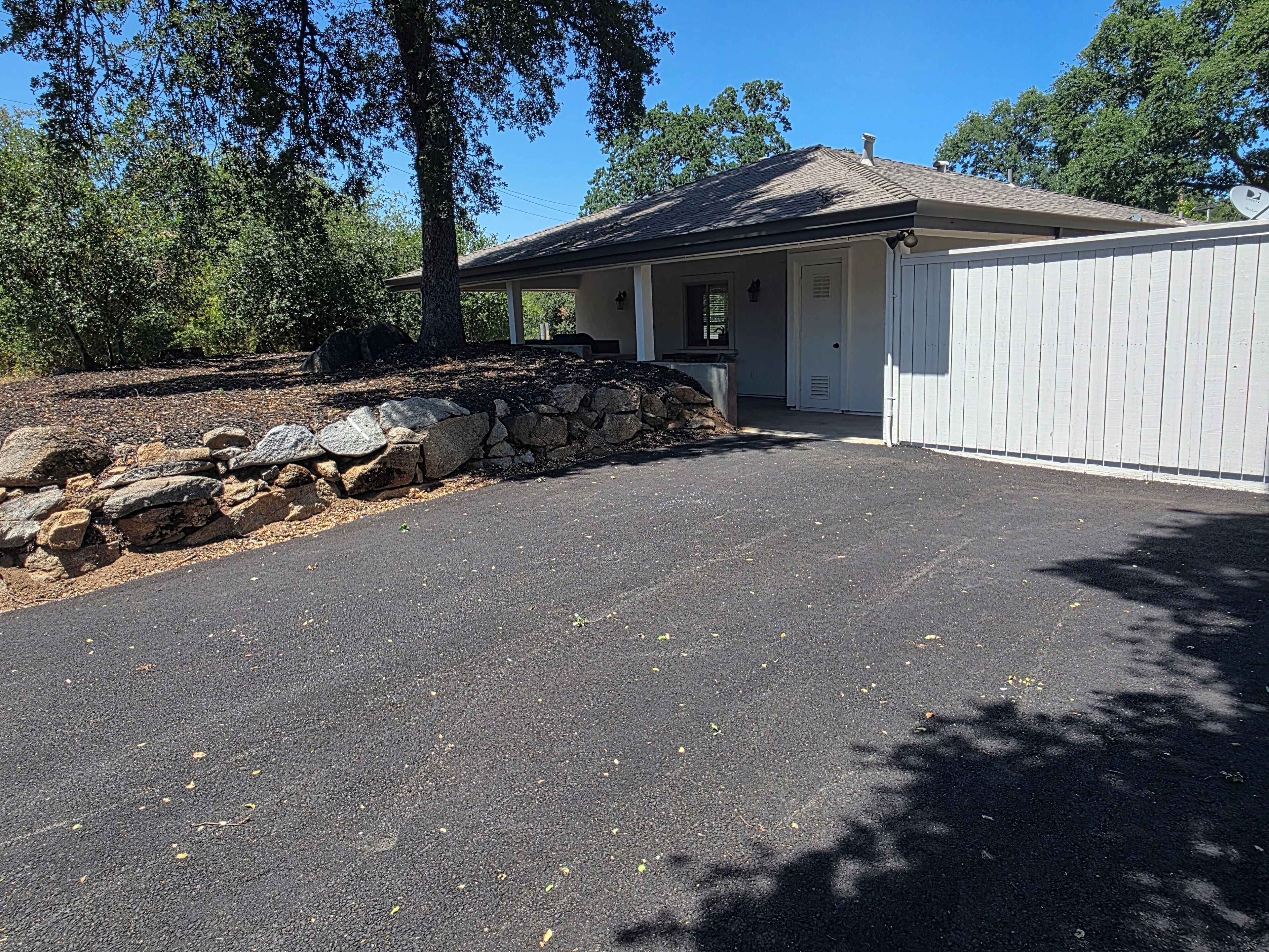A residential property with a stone retaining wall, a garage, and a driveway.