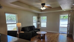 A spacious living room with a black sofa, a small round table, and a ceiling fan.