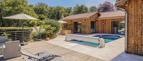 A wooden deck with lounge chairs and a swimming pool.