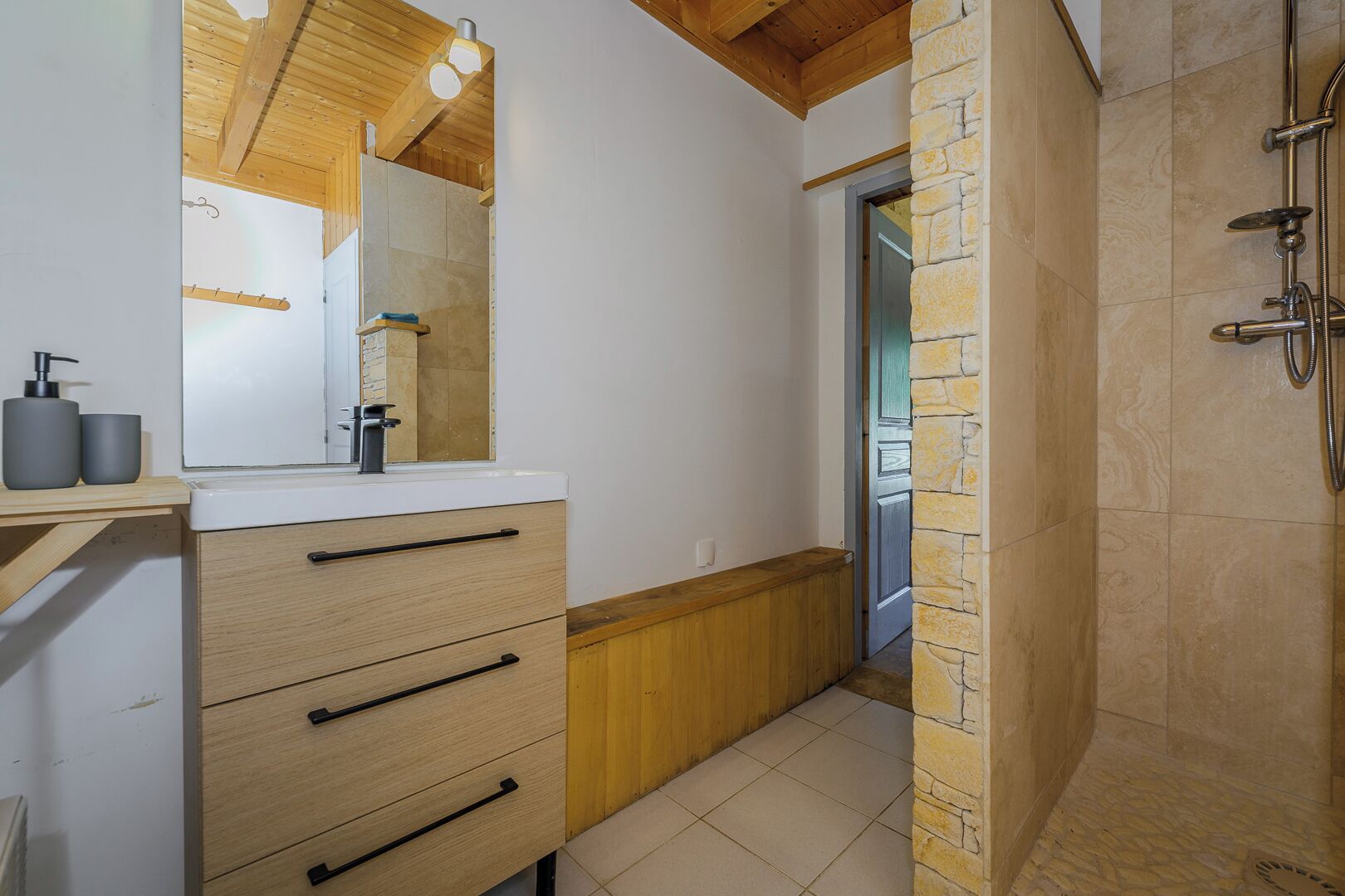 Un baño moderno con tocador de madera, un espejo grande y zona de ducha.