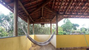 A covered outdoor area with a hammock, yellow walls, and a tiled floor.