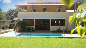 A two-story house with a swimming pool in the front yard.