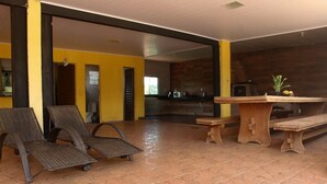A spacious indoor area with a tiled floor, a wooden bench, and two wicker chairs.