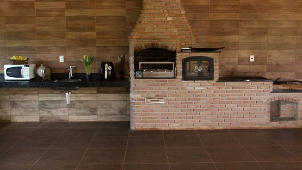 A kitchen with a brick oven, a microwave, and a sink.