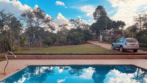 A swimming pool with a clear blue water surface, surrounded by a brick patio.