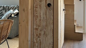 A wooden door with a rustic finish, a staircase with wooden steps, and a view of a window with greenery outside.