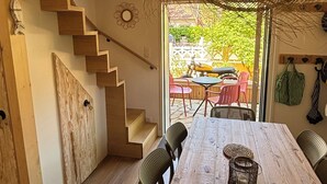 A wooden dining table with chairs, a staircase, and a hanging light fixture.