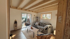A cozy living room with a wooden ceiling, a sofa, a coffee table, and a wicker chair.
