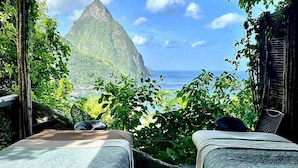 A room with two beds, a wooden floor, and a view of a mountain and ocean. - Picturesque Escape w/Spa & pool | Near Soufrière Beach & Tet Paul Nature Trail (Palmiste)