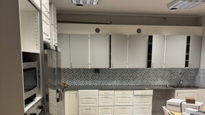 A modern kitchen with white cabinets, a built-in oven, and a wooden countertop. - Ansgarsgården (Flen)