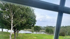 A view through a window of a grassy area with trees and a soccer field. - Ansgarsgården (Flen)