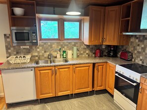 A kitchen with wooden cabinets, a microwave, a sink, a stove, and a toaster.