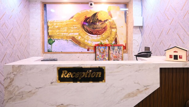 Un mostrador de recepción con encimera de mármol, un letrero que dice 'Reception', una escultura decorativa de una mano, un pequeño modelo de casa y un teléfono.