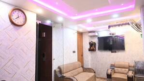 Una sala de estar con un sofá, un sillón reclinable, un televisor montado en la pared y un reloj.