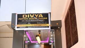 Una Pensión Divya con entrada de vidrio, un letrero y un pequeño área de estar interior visible a través del vidrio.