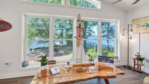 Ein Zimmer mit großen Fenstern mit Blick auf einen See, einem Holztisch und einem Schild mit der Aufschrift 'Lake Murray'.
