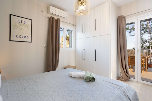 A bedroom with a bed, a window, a wardrobe, and a view of the outside.