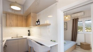 A modern kitchen with a white countertop, wooden cabinets, and a bar stool. - Kalamata Cozy Nest With Panoramic Views (Kalamata)