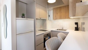 A modern kitchen with white cabinetry, a built-in oven, a sink, and a small plant on the countertop. - Kalamata Cozy Nest With Panoramic Views (Kalamata)