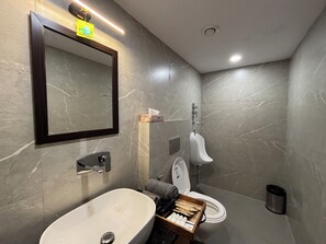 A modern bathroom with a marble wall, a sink, a mirror, a urinal, and a toilet. - Housr Sector 28 Gurgaon Near IFFCO Chowk (Gurugram)