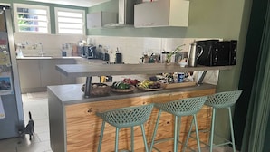 Une cuisine avec un îlot central en bois, des tabourets de bar et un évier.
