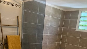 Une salle de bain équipée d’une baignoire, d’une douche et d’un meuble-lavabo avec un miroir.