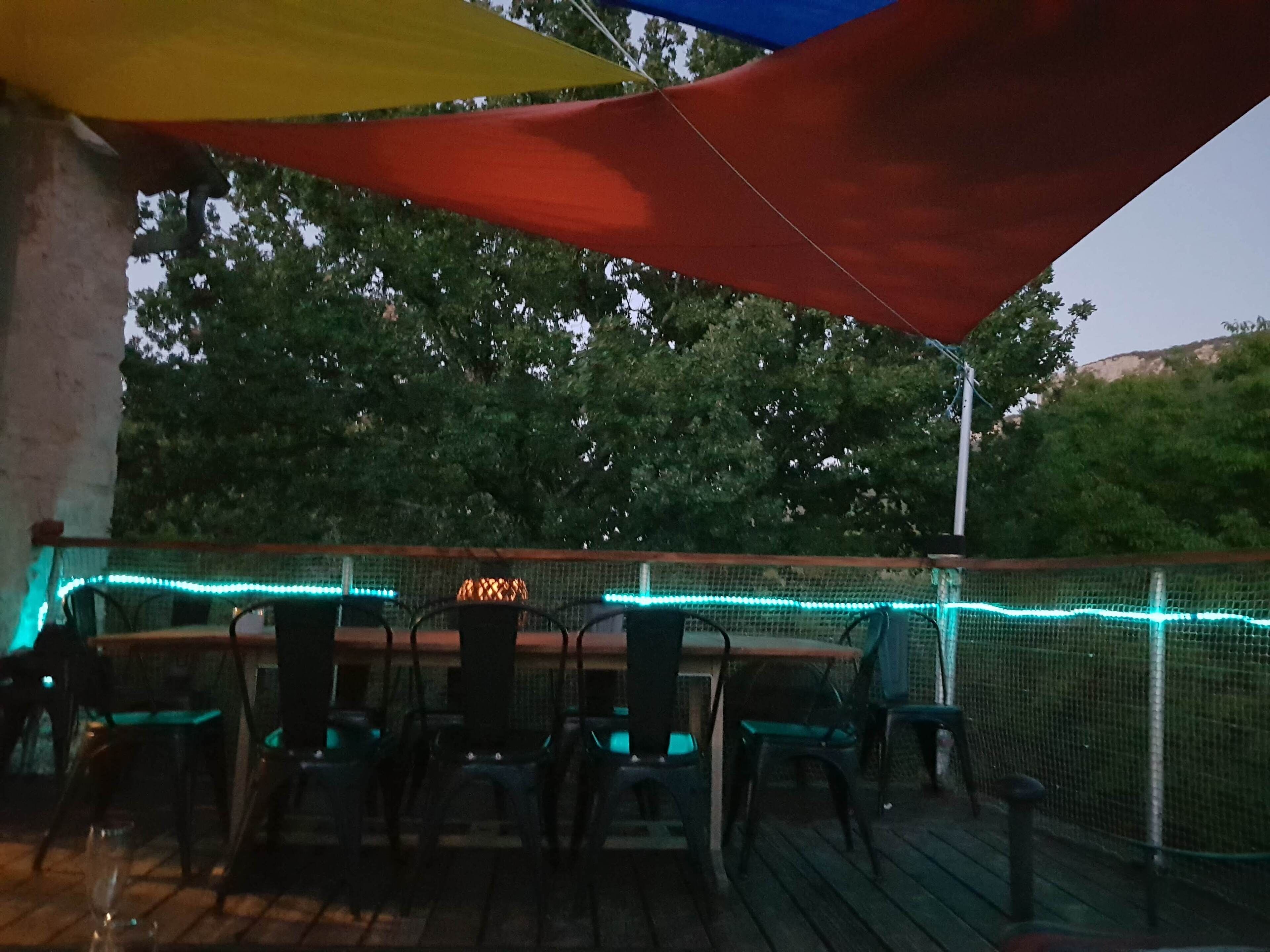 An outdoor dining area with a table and chairs, a string of lights, and a netted enclosure.