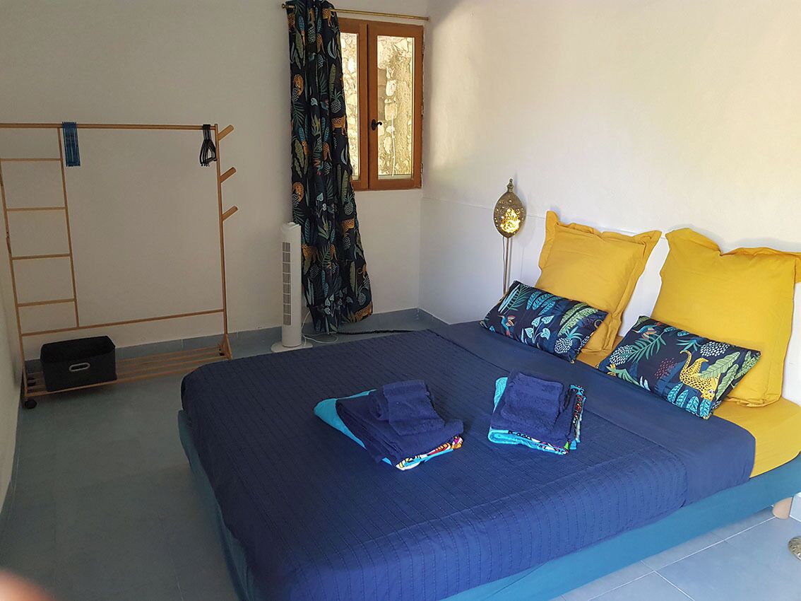 Una camera da letto con un letto, cuscini, una scala, una finestra e una lampada da terra.