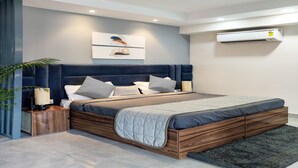 Une chambre à coucher moderne avec un cadre de lit en bois, une couvre-lit matelassée grise et un climatiseur fixé au mur.