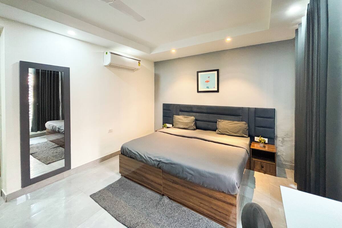 A modern bedroom with a bed, bedside tables, a ceiling fan, and a framed picture on the wall.