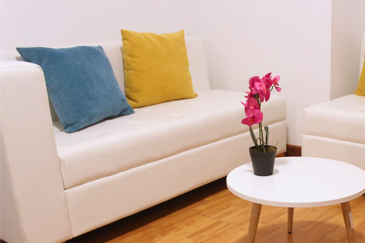 Ein Zimmer mit zwei weißen Sofas, jedes mit einem blau-gelben Kissen, und einem kleinen weißen Tisch mit einer Blumentopf in der Mitte.