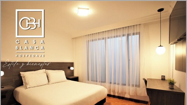 Habitación de hotel con una cama grande, un escritorio y una ventana con cortinas traslúcidas.