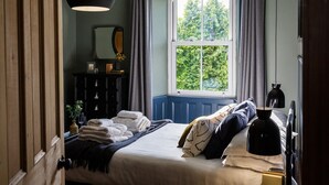 Ein Schlafzimmer mit einem Bett, einem Schminktisch, einem Fenster mit Vorhängen und einer Hängeleuchte.