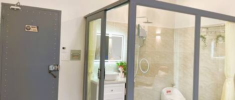 A modern bathroom with a glass-enclosed shower, a toilet, and a sink with a mirror.