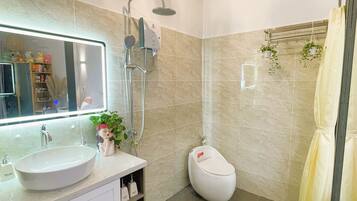 A modern bathroom with a large mirror, a sink, a toilet, and a shower.