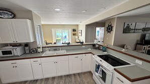 Una cocina moderna con armarios blancos, horno integrado y una isla grande con lavamanos.