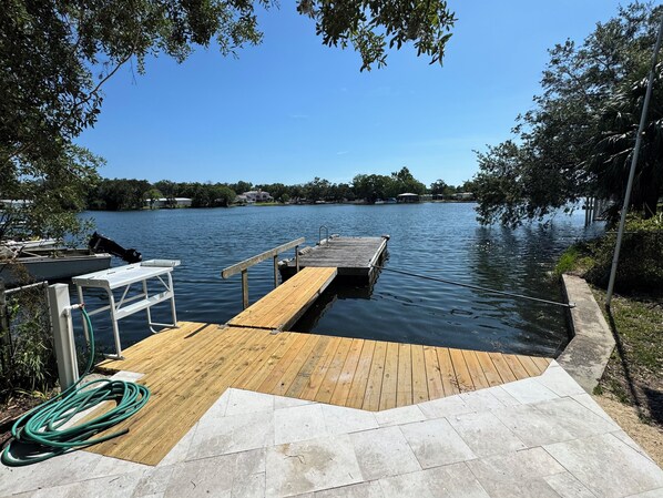A wooden dock extending into a calm lake, surrounded by trees and a clear sky.